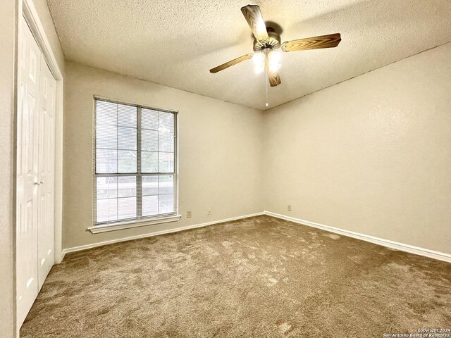 empty room featuring carpet, ceiling fan, and a textured ceiling