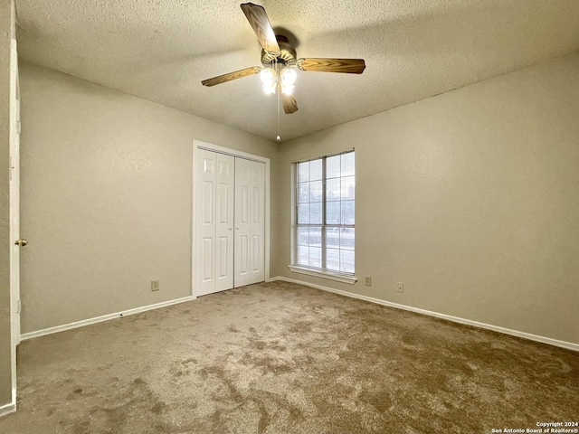 unfurnished bedroom with ceiling fan, carpet floors, a textured ceiling, and a closet