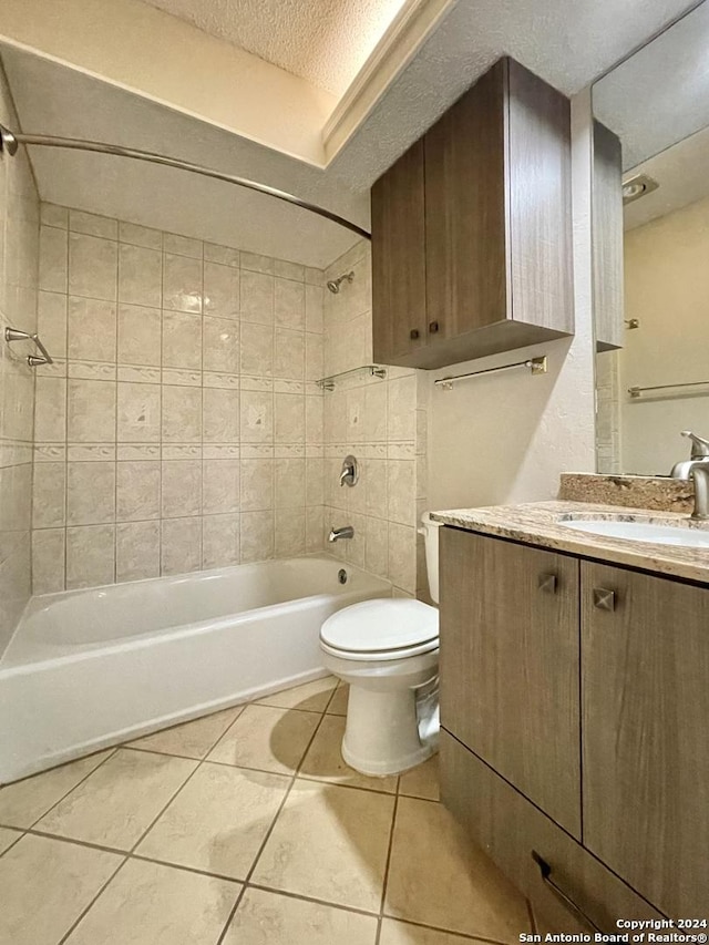 full bathroom with vanity, tile patterned floors, tiled shower / bath combo, toilet, and a textured ceiling