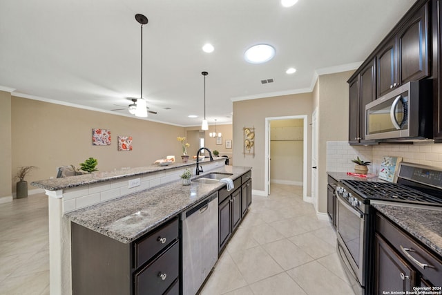 kitchen with light stone countertops, decorative light fixtures, stainless steel appliances, sink, and dark brown cabinetry