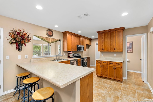 kitchen featuring a kitchen breakfast bar, kitchen peninsula, sink, and appliances with stainless steel finishes