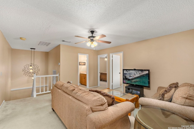 living room with ceiling fan, light colored carpet, and a textured ceiling