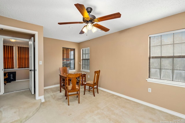 dining space with light carpet, ceiling fan, and a textured ceiling