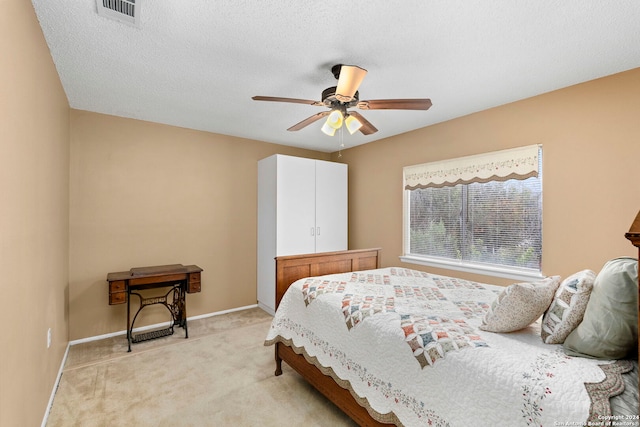 bedroom with ceiling fan, light carpet, and a textured ceiling