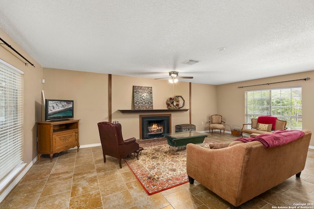 living room featuring ceiling fan and a textured ceiling