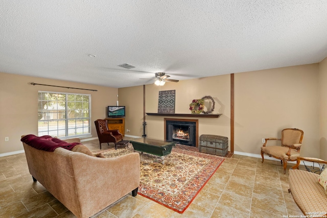 living room featuring ceiling fan and a textured ceiling