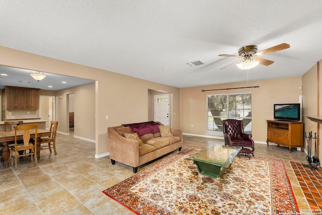 living room featuring ceiling fan and a textured ceiling