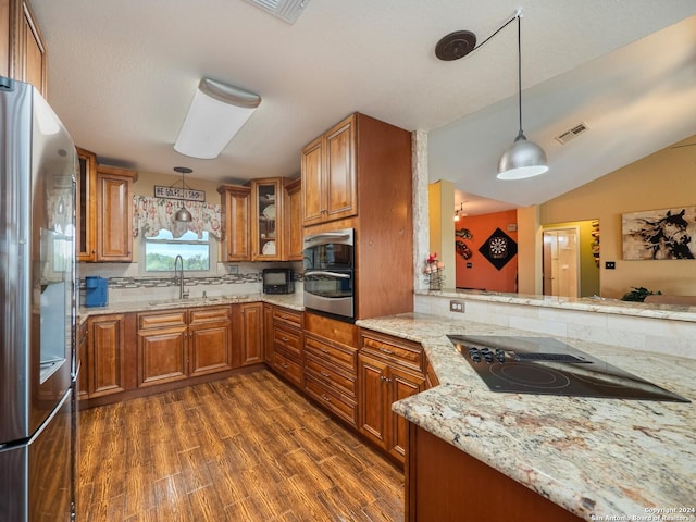 kitchen featuring appliances with stainless steel finishes, dark hardwood / wood-style flooring, light stone counters, hanging light fixtures, and lofted ceiling