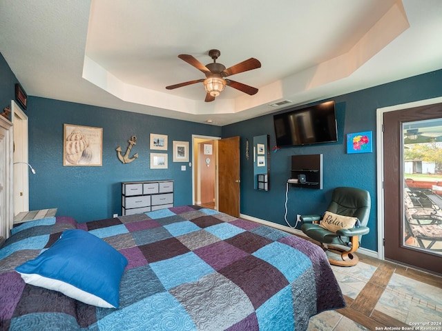 bedroom with access to outside, a tray ceiling, and ceiling fan