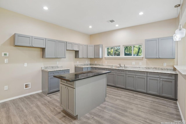 kitchen featuring pendant lighting, gray cabinets, a kitchen island, and light hardwood / wood-style flooring