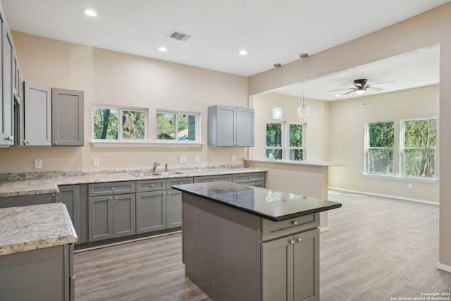 kitchen featuring light hardwood / wood-style flooring, a kitchen island, gray cabinetry, and sink