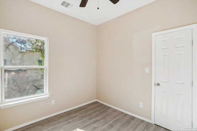 empty room with ceiling fan, a healthy amount of sunlight, and hardwood / wood-style flooring