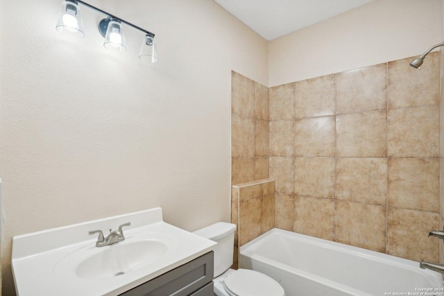 full bathroom featuring vanity, tiled shower / bath, and toilet