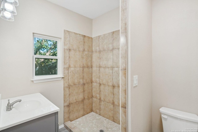 bathroom featuring toilet, vanity, and tiled shower