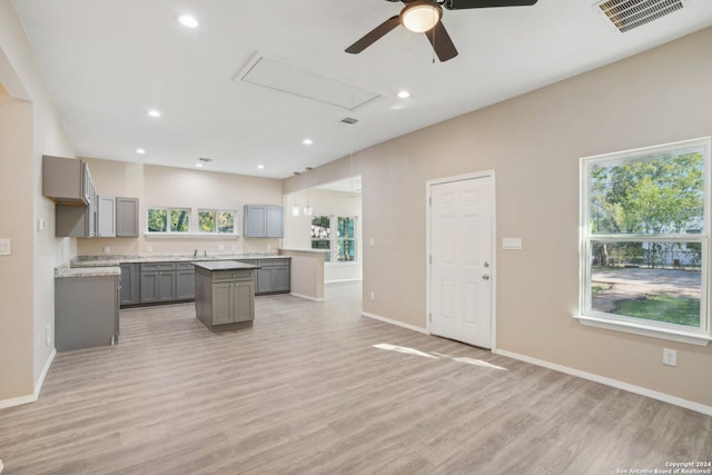 kitchen with a center island, light hardwood / wood-style flooring, ceiling fan, gray cabinets, and decorative light fixtures