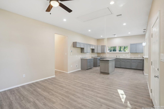 kitchen featuring gray cabinetry, ceiling fan, sink, light hardwood / wood-style flooring, and a center island