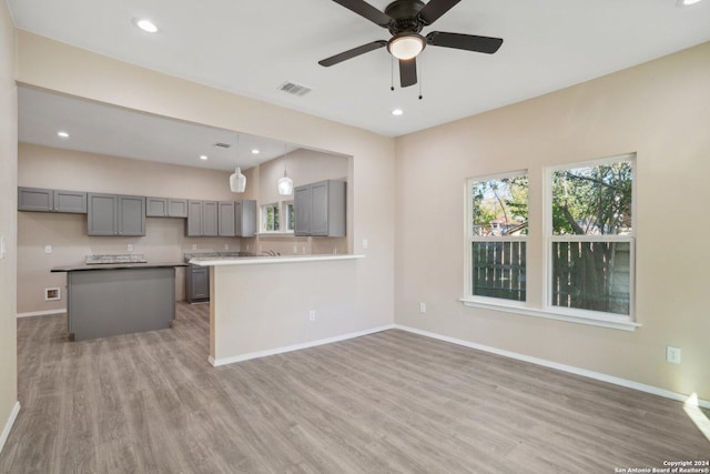 kitchen with kitchen peninsula, pendant lighting, gray cabinetry, and wood-type flooring