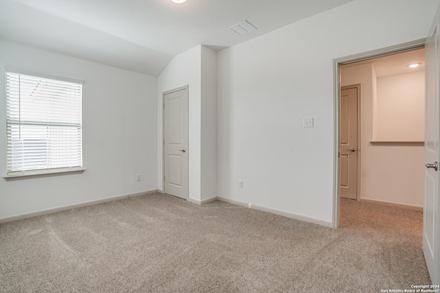 empty room with light colored carpet and lofted ceiling