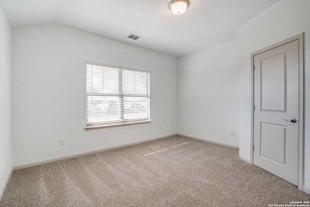 spare room featuring light carpet and vaulted ceiling