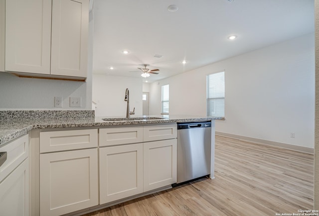 kitchen with light stone countertops, white cabinetry, dishwasher, sink, and light wood-type flooring