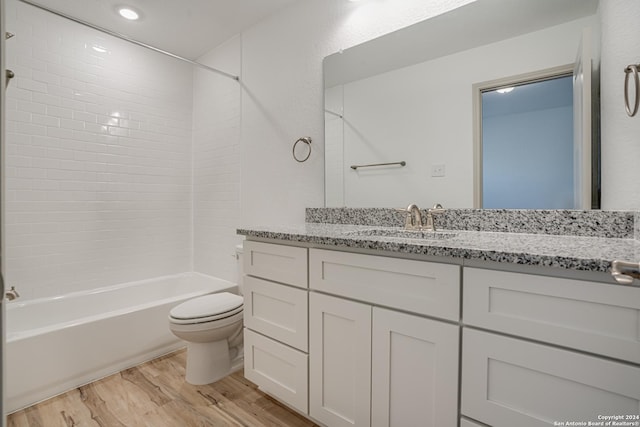 full bathroom featuring tiled shower / bath, hardwood / wood-style floors, vanity, and toilet