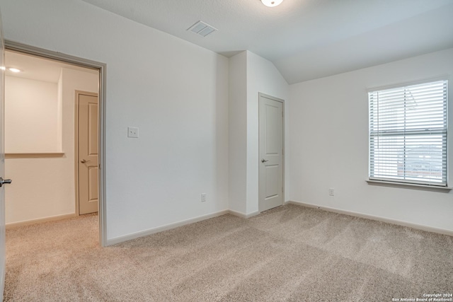 carpeted empty room with lofted ceiling