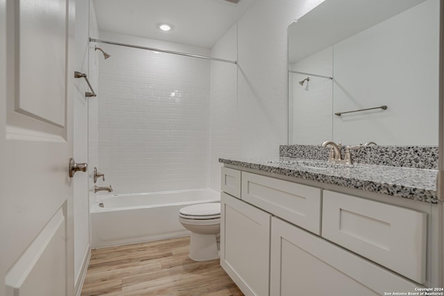 full bathroom with hardwood / wood-style floors, vanity, toilet, and tiled shower / bath