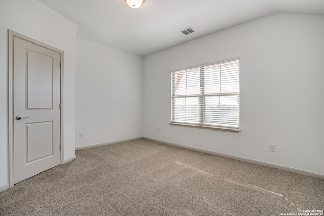 carpeted spare room with vaulted ceiling