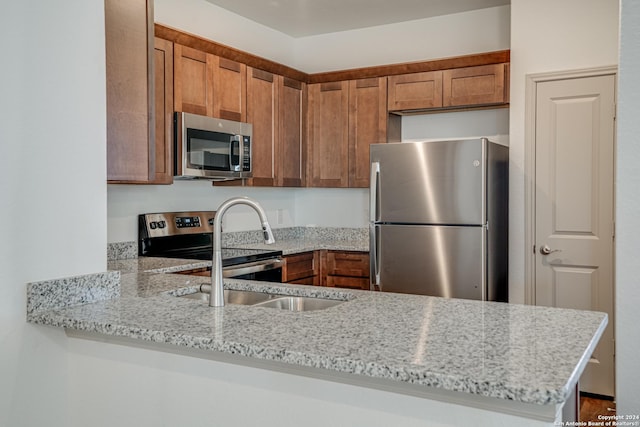 kitchen with light stone countertops, appliances with stainless steel finishes, and kitchen peninsula