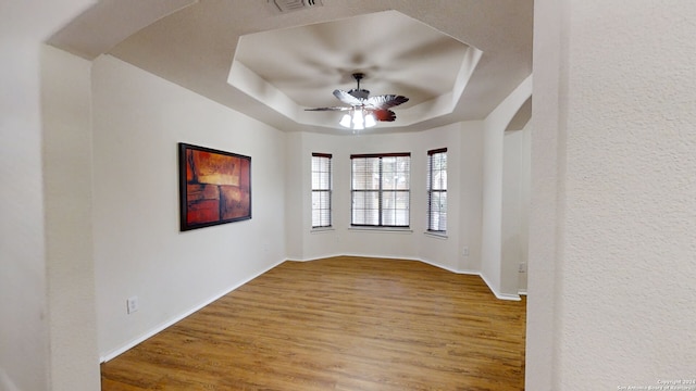 spare room with hardwood / wood-style floors, ceiling fan, and a tray ceiling