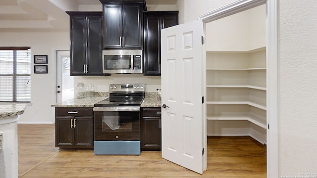 kitchen with light stone counters, light hardwood / wood-style floors, and appliances with stainless steel finishes