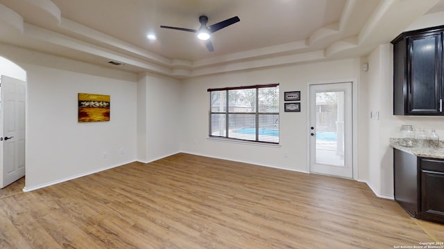 unfurnished living room featuring light hardwood / wood-style flooring, a raised ceiling, and ceiling fan