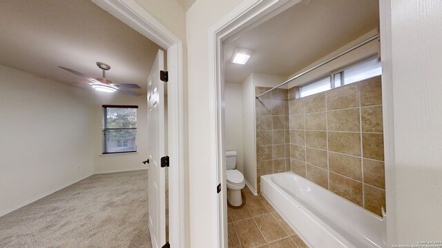 bathroom with tile patterned flooring, tiled shower / bath combo, ceiling fan, and toilet