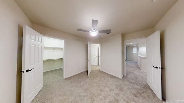 unfurnished bedroom with ceiling fan, light colored carpet, a spacious closet, and a closet