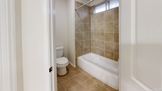 bathroom featuring tile patterned flooring, tiled shower / bath combo, and toilet