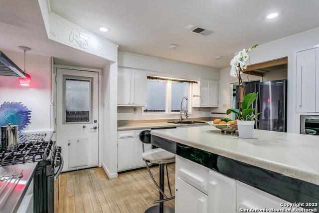 kitchen with white cabinetry, sink, pendant lighting, appliances with stainless steel finishes, and light wood-type flooring