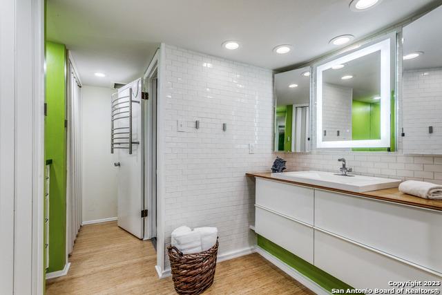 bathroom featuring hardwood / wood-style flooring, vanity, and tasteful backsplash