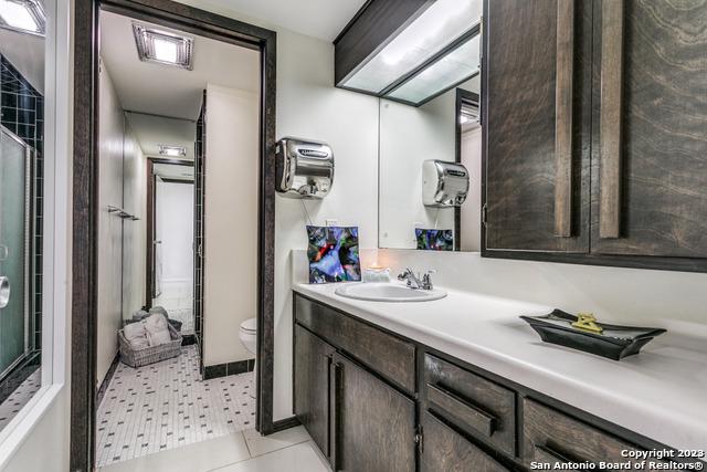 bathroom with tile patterned flooring, a shower, vanity, and toilet