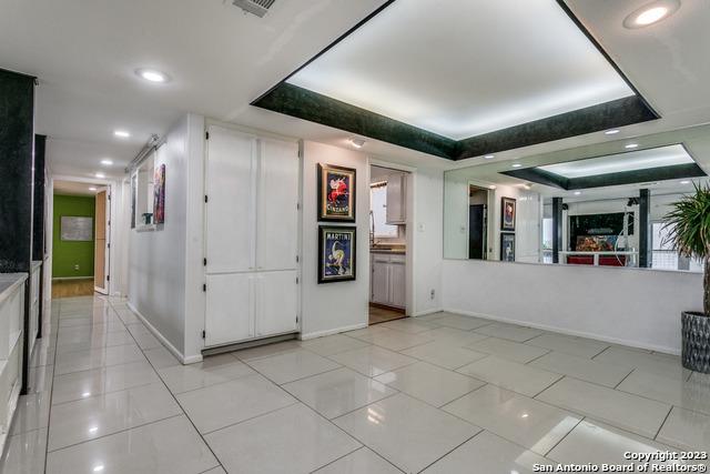 unfurnished living room featuring a raised ceiling and light tile patterned floors