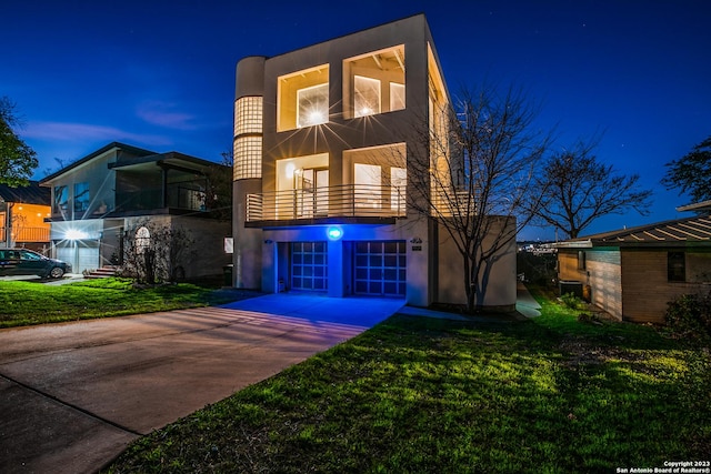 modern home with a balcony, a garage, and a front lawn