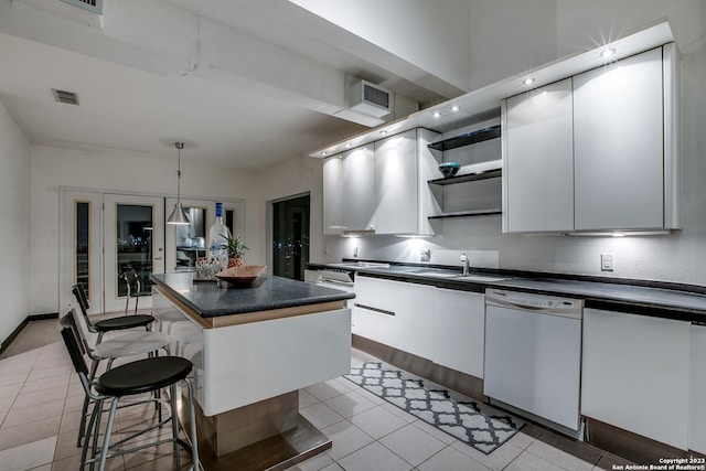 kitchen featuring white dishwasher, a center island, white cabinetry, and pendant lighting