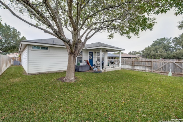 back of property with a yard, ceiling fan, and central air condition unit