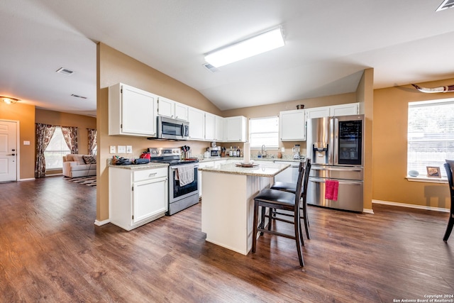 kitchen with dark wood-type flooring, white cabinets, a breakfast bar area, a kitchen island, and appliances with stainless steel finishes