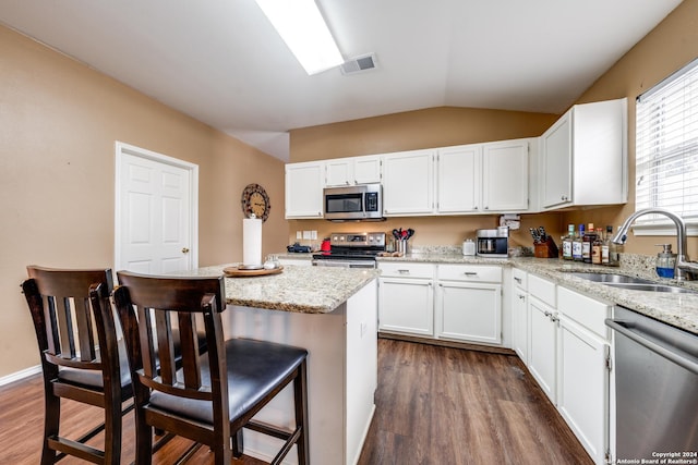 kitchen featuring a breakfast bar, sink, vaulted ceiling, white cabinetry, and stainless steel appliances