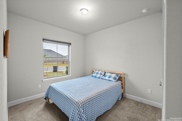 bedroom with light colored carpet and a textured ceiling