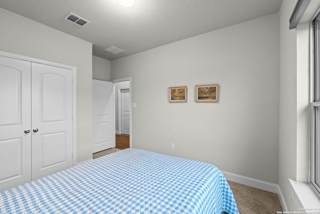 carpeted bedroom featuring a closet and a textured ceiling