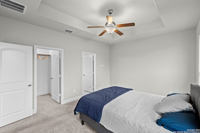 carpeted bedroom with a raised ceiling and ceiling fan