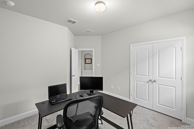 carpeted office featuring a textured ceiling