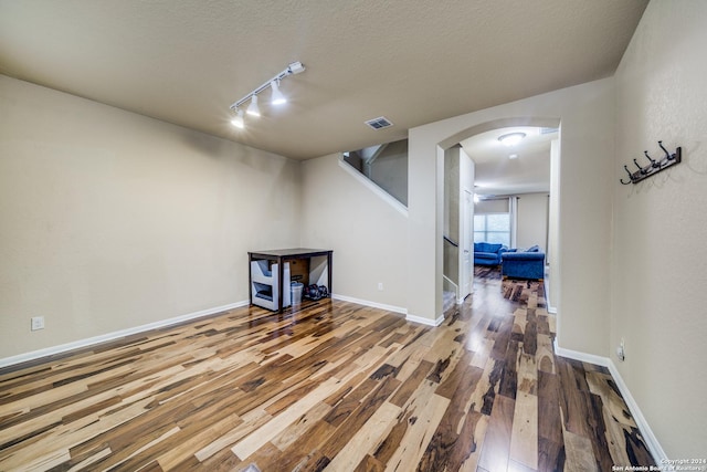 interior space with hardwood / wood-style floors, a textured ceiling, and track lighting