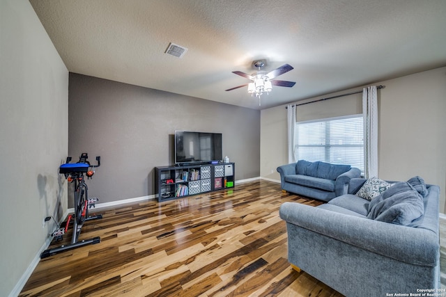 living room with ceiling fan, hardwood / wood-style floors, and a textured ceiling